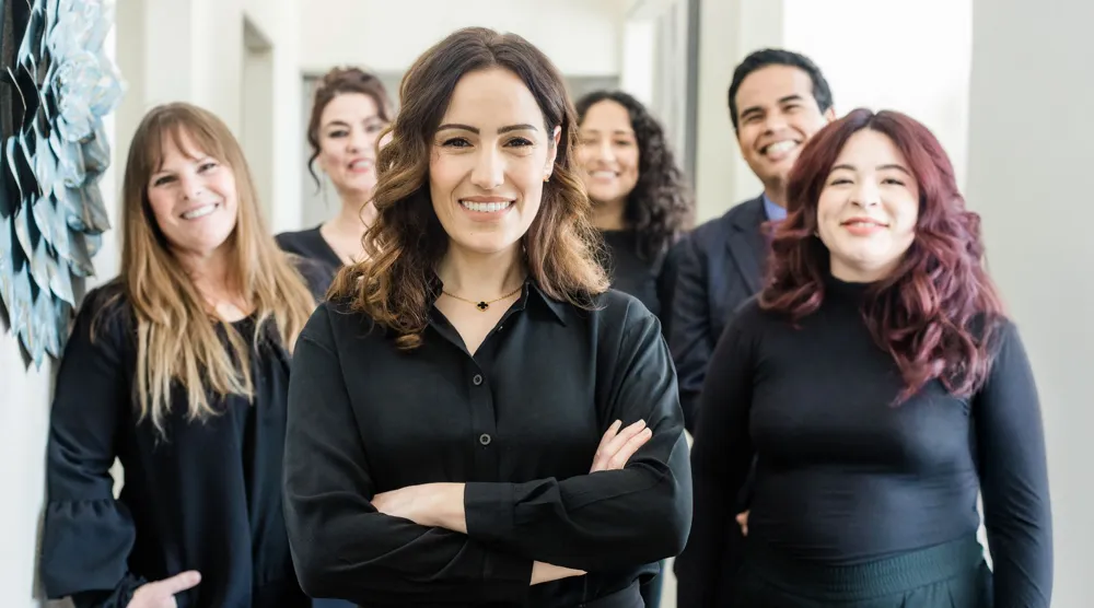 Five smiling team members standing together in a bright office