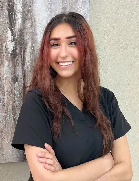 Arissa Garcia smiling in black scrubs with her arms crossed